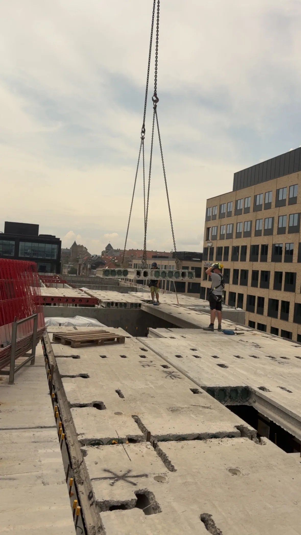 Kranløft over dækelementer på en byggeplads.