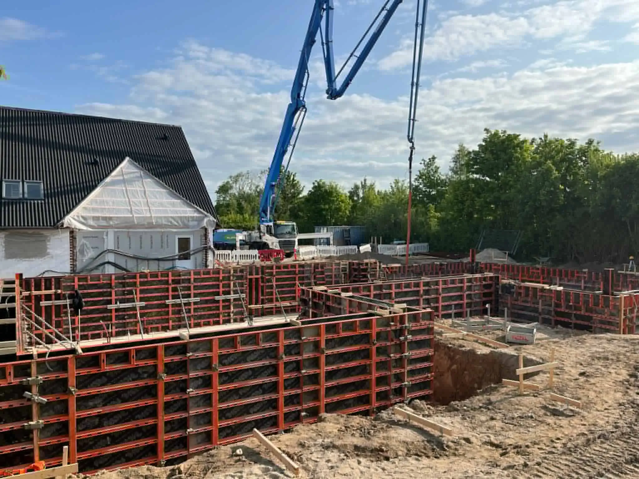 Vægforskalling og betonpumpe på en byggeplads.