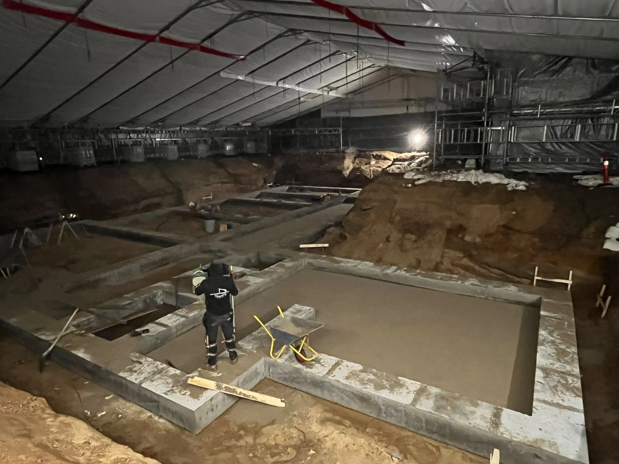 Betonarbejde under udførelse på en overdækket byggeplads.