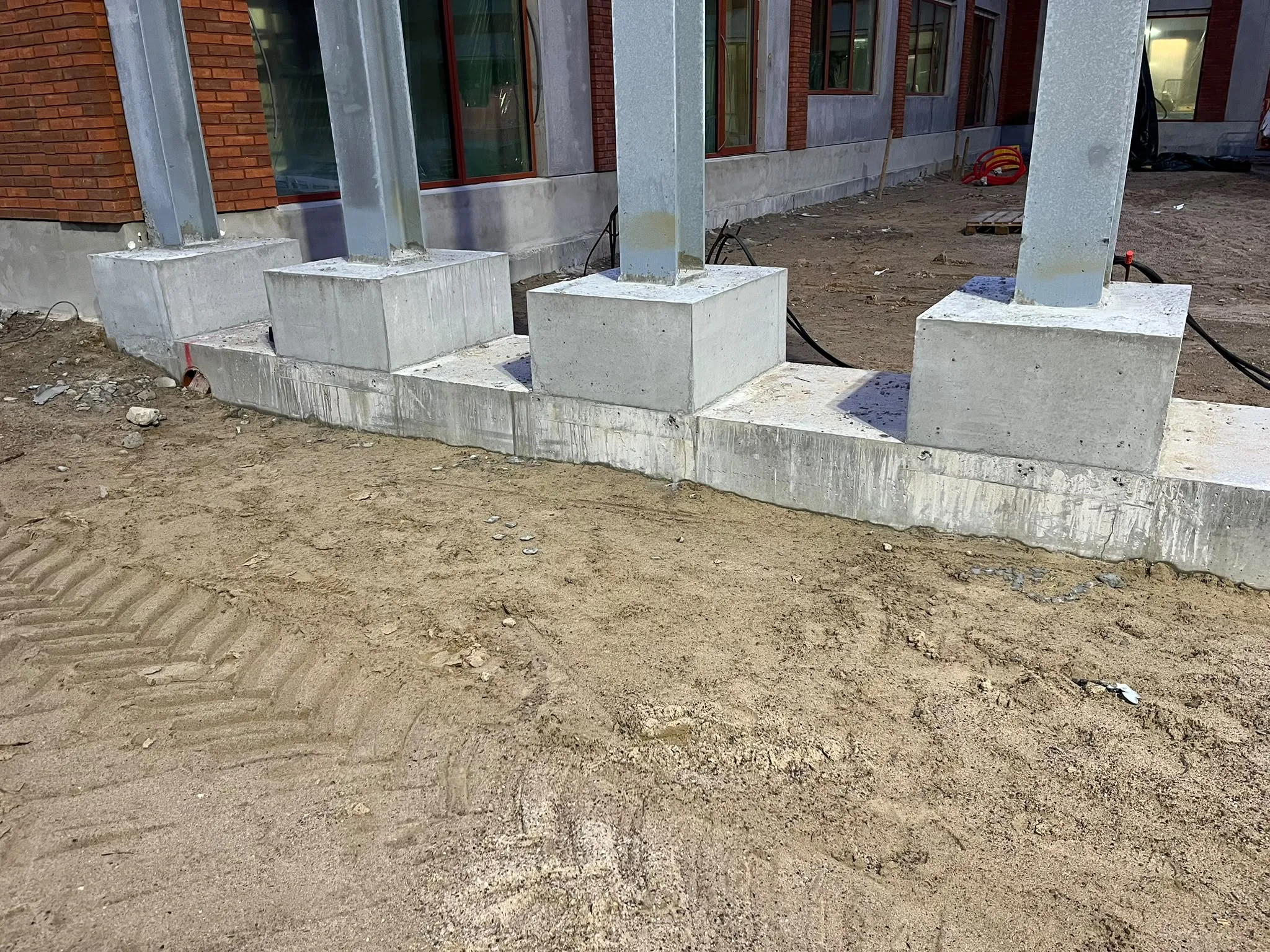 Betonfundamenter omkring stålsøjler langs en bygning.